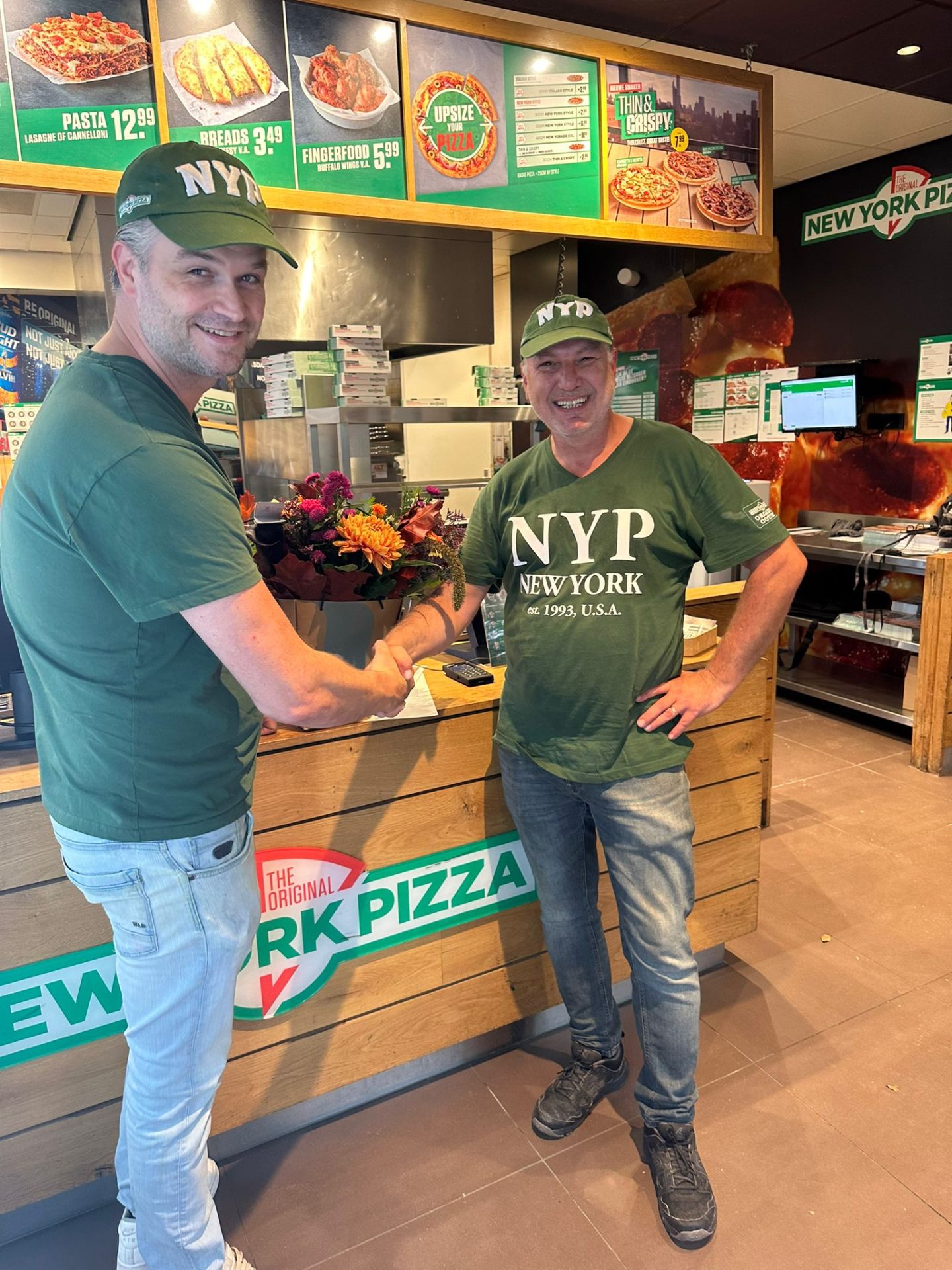 Aangenomen kandidaat ontvangt bloemen bij New York Pizza.